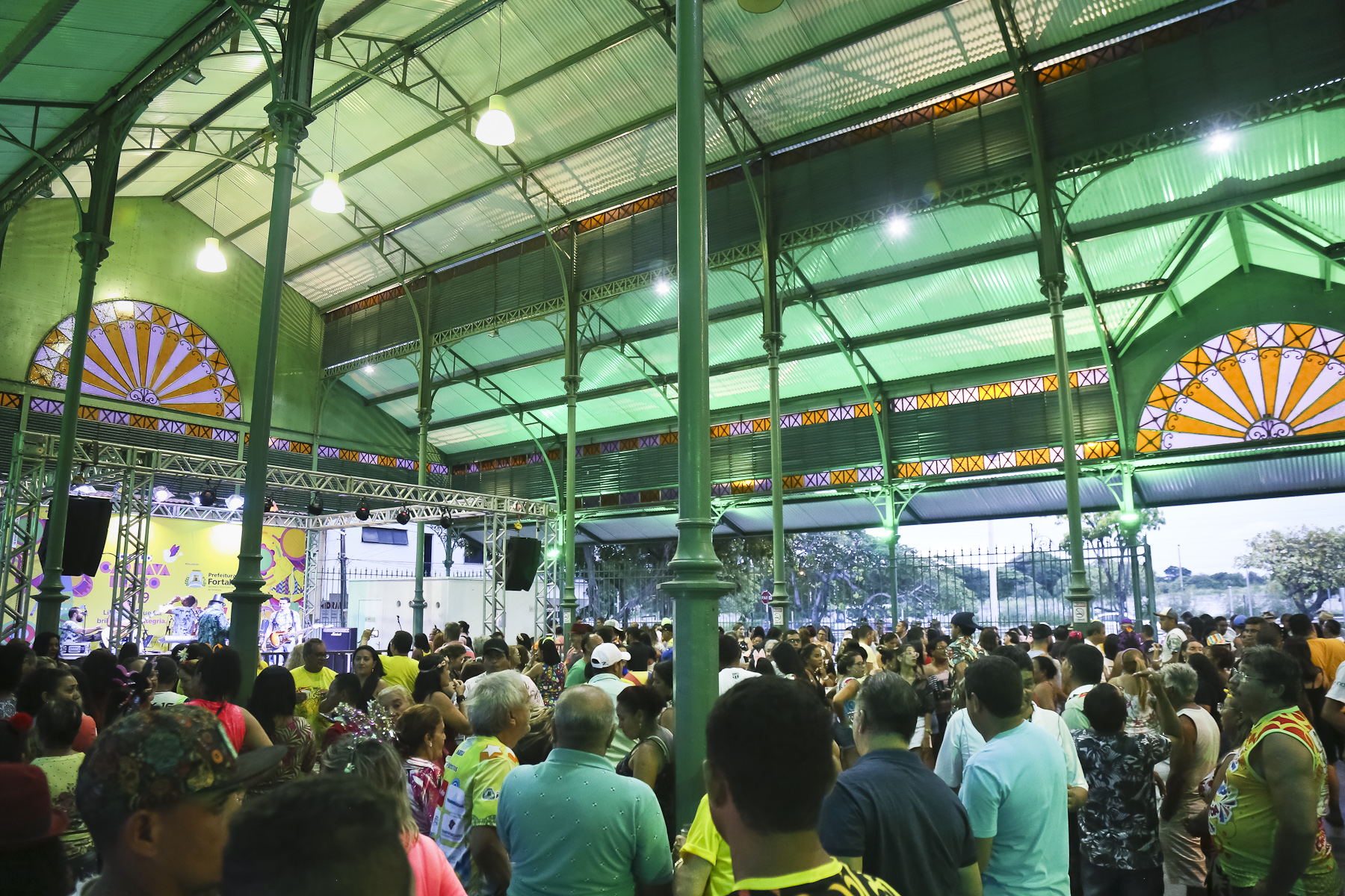 interior do mercado da aerolândia mostrando várias pessoas dançando e um palco com artistas